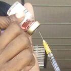 A photo of a vaccine vial and vaccination needle