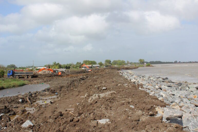 Excavators and a truck operating on the sea dike construction site.